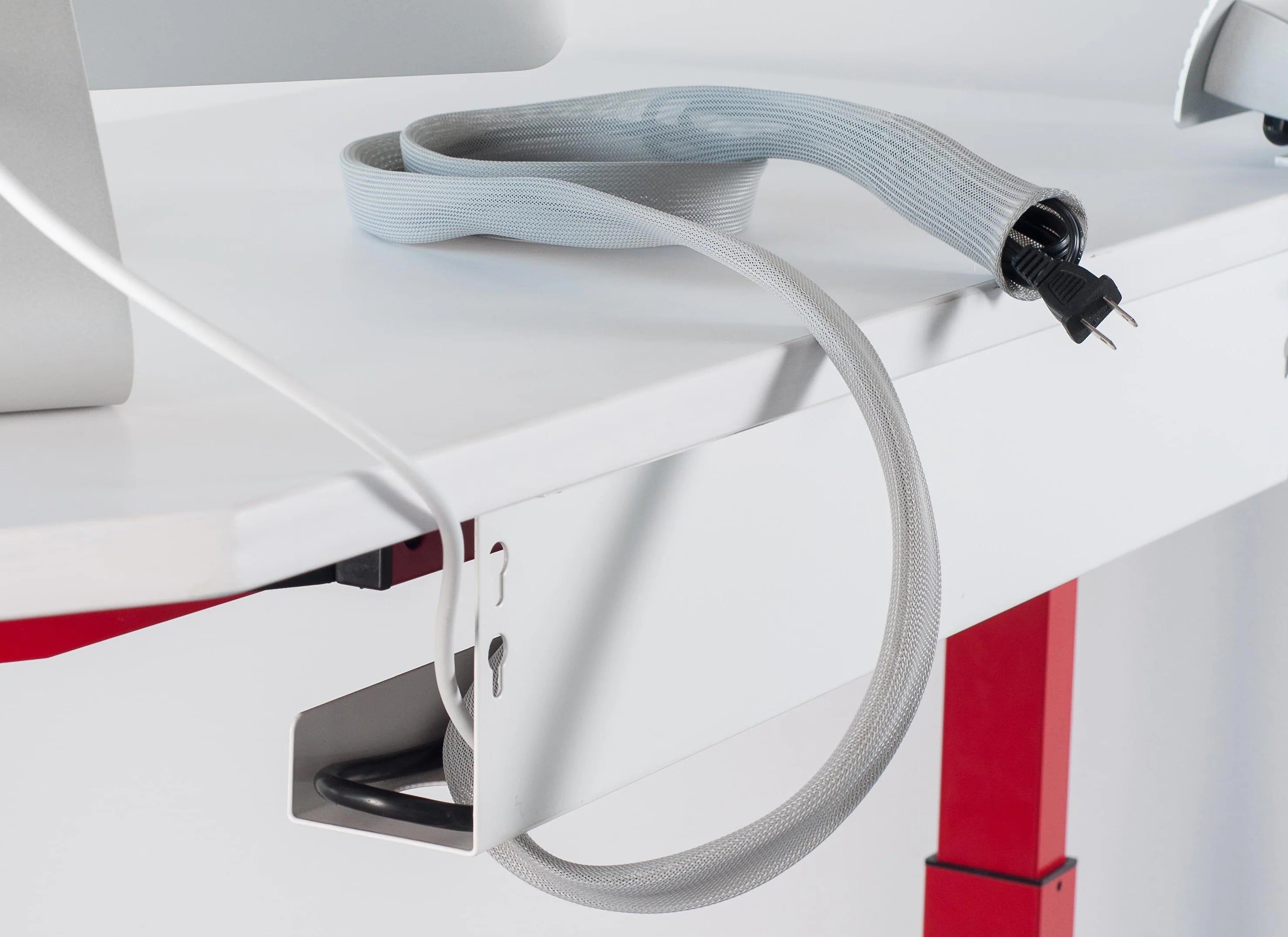 Braided cable sleeve routing cables down the desk leg to the floor